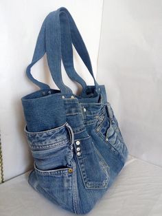 a purse made out of old jeans is hanging on a white wall with a chain attached to it