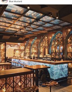 the interior of a restaurant with wooden tables and chairs, lights on the ceiling, and an elaborately decorated bar