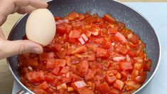 someone is cooking tomatoes and an egg in a skillet on the stove with a spatula