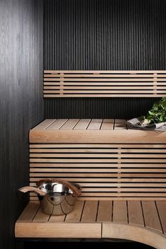 a wooden bench with two bowls on it and a plant in the corner next to it