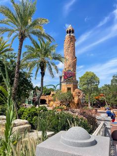 there is a large tower in the middle of a park with palm trees around it