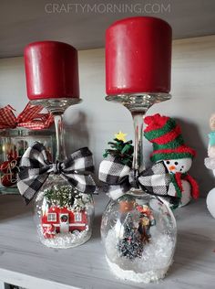 christmas ornaments are sitting on a mantle with red candles and snow globes in them