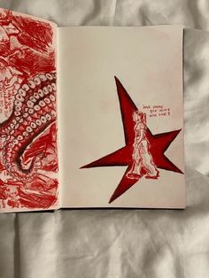 an open book with red ink on it and a drawing of a woman holding a star