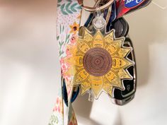 a cell phone hanging from a keychain that has a flower design on it