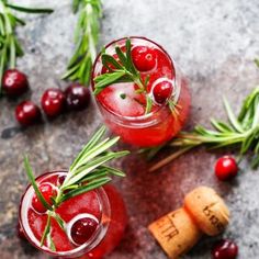 two glasses filled with cranberry shrub and rosemary garnish on top of a table