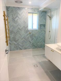 a bathroom with a walk in shower next to a white sink and counter top under a window