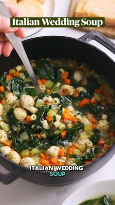 a person is spooning food into a pot with vegetables and bread on the side