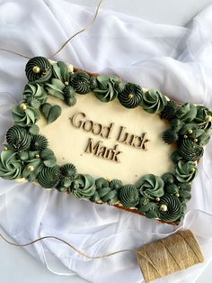 a cake decorated with green leaves and the words good luck mark