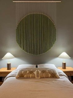 a bed with two lamps on each side and a green curtain hanging over it's headboard