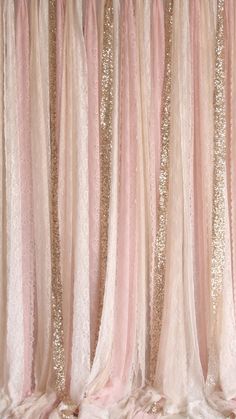 a pink and gold wedding backdrop with sequins on the top, hanging from a ceiling