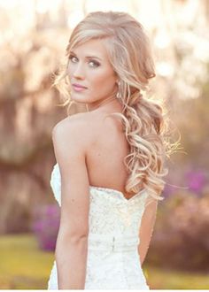 a woman with long blonde hair wearing a wedding dress and looking at the camera while she is