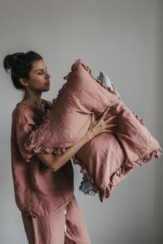 a woman holding a large pillow with ruffled edges