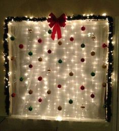 christmas lights and ornaments are hung on the wall in front of a window with a red bow