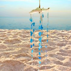 a wind chime on the beach with blue glass pieces hanging from it's sides