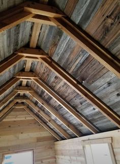 the inside of a building with wooden walls and beams on top of it's roof