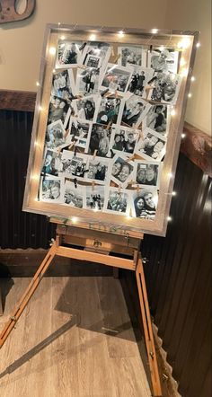 an easel with pictures on it in front of a wall and some lights around the frame