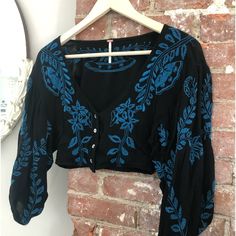 This Is A Black & Royal Blue Top Designed By Free People It’s Short With 3/4 Length Balloon Sleeves , Four Buttons In Front , It’s A Midriff Style , Size 4 .( M) It Is A Embroidered Design.. Very Fashionable!!! Pair With Bell Bottom Jeans And Platform Shoes For A New Boho Look !! It Is Nwot Black V-neck Tops With Floral Embroidery, Fitted Black Embroidered Top For Festival, Black Long Sleeve Embroidered Top For Summer, Black Embroidered Long Sleeve Top For Summer, Black Long Sleeve Embroidered Top, Black Fitted Bohemian Embroidered Top, Fitted Black Bohemian Embroidered Top, Black Cropped Cotton Blouse, Casual Embroidered Cropped Blouse