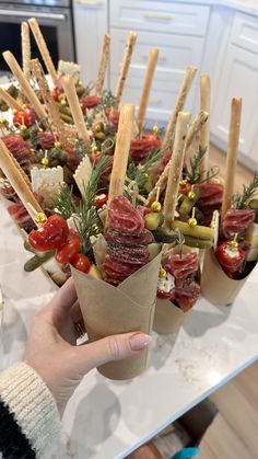 a person holding food in their hand on a table with other food items and utensils