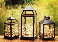 three lanterns with fairy lights on them