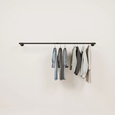 several shirts hanging on a rail in front of a white wall