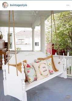 a white porch swing with pillows on it