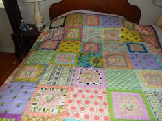 a bed with a colorful quilt on it and two lamps in the corner next to it