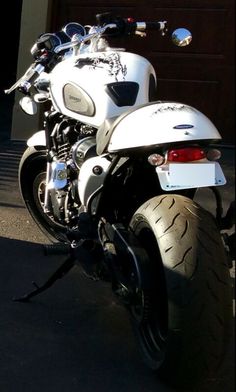 a white motorcycle parked in front of a garage