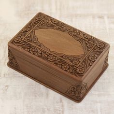 an intricately carved wooden box sits on a white tableclothed surface and looks like it has been made out of wood