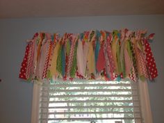 the window valance is decorated with polka dots and colorful ribbons hanging from it's rod