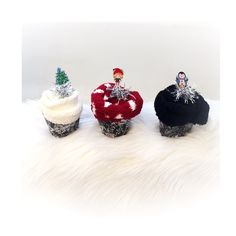 three cupcakes with frosting and decorations on them sitting on a fur surface