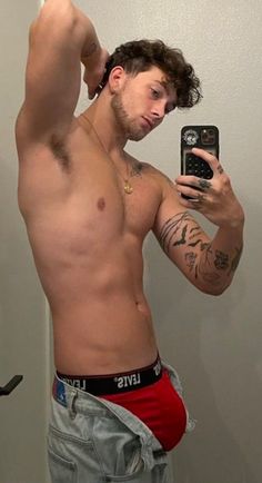 a shirtless man taking a selfie with his cell phone