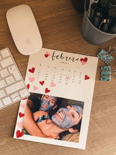 a desk with a calendar, keyboard and mouse next to it on top of a wooden table