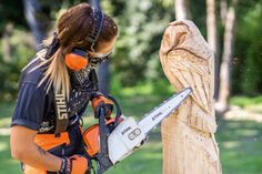 a woman is cutting wood with a chainsaw