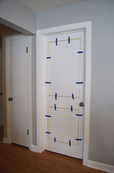 an open door with blue tape taped to it and the room is painted in white