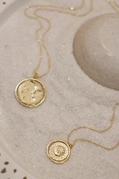 A gold rotating necklace which features the face of the sun on one side and the face of the moon on the other. Comes in 2 sizes. Small charm is 1” wide and hangs from a 16” chain Big charm is 1.5” wide and hangs from a 21” chain Silver Sun And Moon Design Gold-plated Necklace, Moon Phase Medallion Necklace In Amulet Style, Gold Moon Phase Amulet Jewelry, Moon Phase Medallion Necklaces Styled As Amulets, Moon Phase Coin Necklace With Round Pendant, Gold Engraved Moon Necklace, Moon Phase Medallion Amulet Jewelry, Gold Medallion Necklace With Moon Charm Pendant, Symbolic Medallion Necklace With Moon Phase