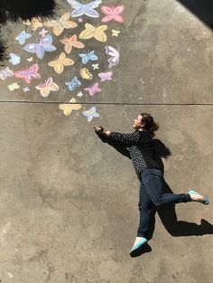 a woman laying on the ground drawing with chalk