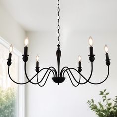 a black chandelier with five lights hanging from it's center, in front of a window