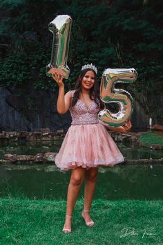 a woman in a pink dress is holding up some balloons and the number five on it