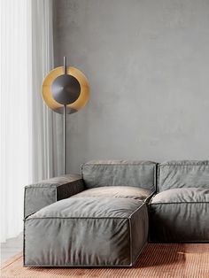 a gray couch sitting on top of a wooden floor next to a lamp in a living room