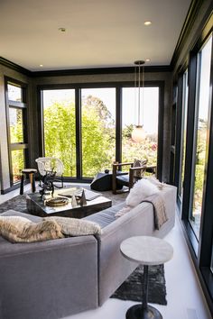 a living room filled with lots of furniture and large windows overlooking the trees in the distance