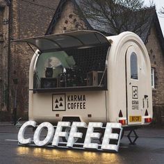 a coffee truck parked in front of a building with the word coffee written on it