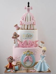 a three tiered cake with figurines on top and an image of a princess