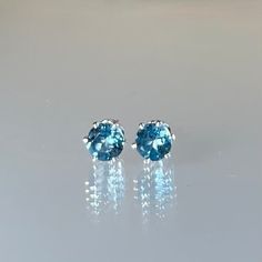 Genuine, sparkling, AAA-rated, 5 mm , teal (blue-green) London blue topaz gemstones set in nickel-free, 925 sterling silver six-prong stud posts. These stud earrings are designed with perfectly matched, round-cut, earth-mined, genuine teal London blue topaz gemstones.  The precisely faceted 5 mm, semi-precious stones are securely set in six-prong sterling silver stud posts and completed with sturdy butterfly ear nuts.  Although not adequately captured in the photos, these gemstones are of exceptional cut, color, and clarity, rendering their glow and sparkle outstanding.  These gemstones are teal-blue (medium blue with traces of green). Topaz is the birthstone for December and is said to bring good fortune, joy, abundance, confidence and good health. While minimal in design, these sparkling Minimalist Blue Birthstone Earrings, Blue Round Stone Earrings For Gift, Blue Topaz Minimalist Jewelry, Classic Blue Earrings For Everyday, Green Topaz, Blue Topaz Earrings, Topaz Earrings, Pretty Bracelets, Blue Gemstones