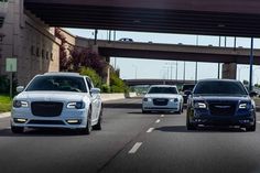 three cars are driving down the road under an overpass in front of another car