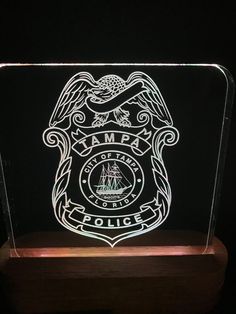 an illuminated police badge is shown on a wooden base with a black background and white lettering