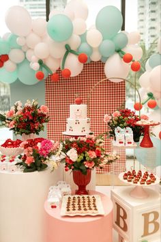 a table topped with cake and flowers next to balloons