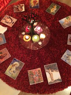 a table topped with pictures and candles on top of a red rug covered in flowers