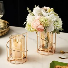 two vases with flowers and candles on a table