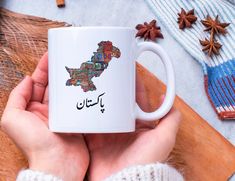 a person holding a coffee mug in their hands with the map of pakistan printed on it