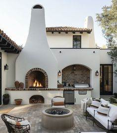 an outdoor kitchen and living room area with fire pit in the center, patio furniture on either side